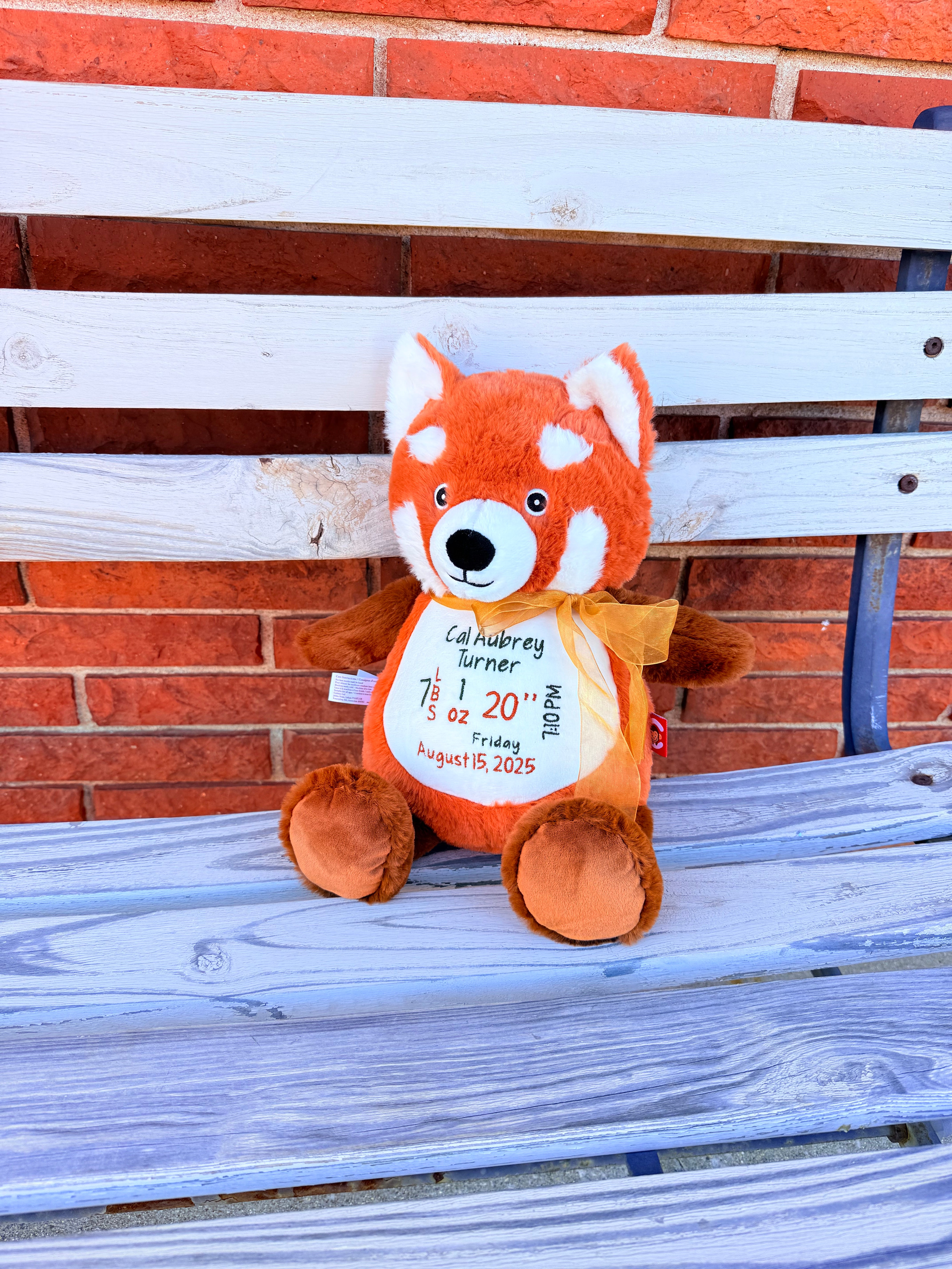Plush Red panda toy with a label on a wooden surface