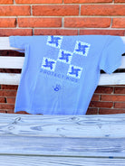 Blue sweatshirt with a logo and text hanging on a clothesline against a brick wall.