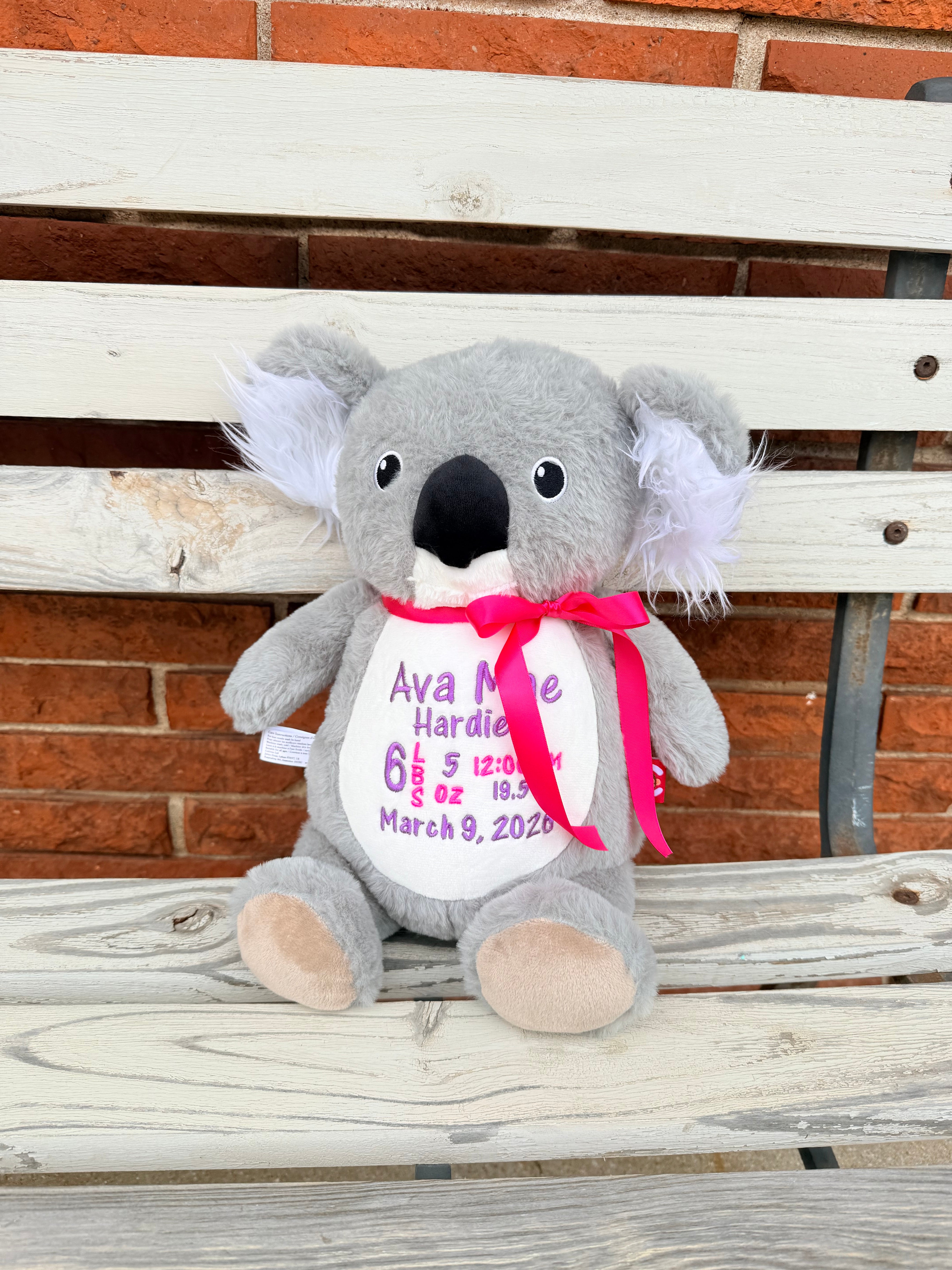 Gray stuffed koala bear with a personalized tag on a wooden background